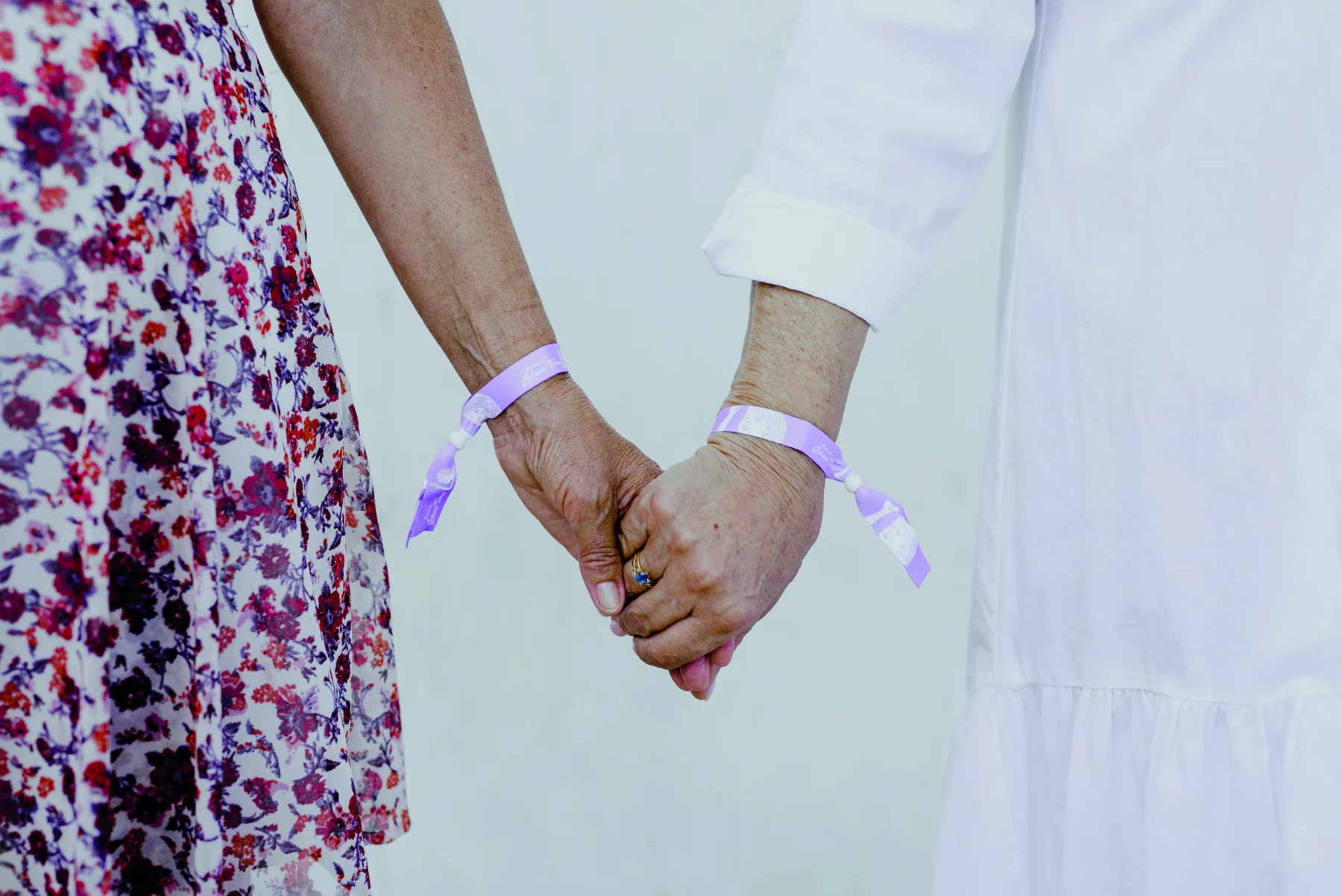 Dos voluntarias de la Asociación Elena Torres se dan la mano, unidas por sus pulseras solidarias